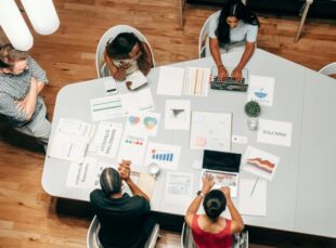 Group discussing marketing strategies at a table with laptops and charts