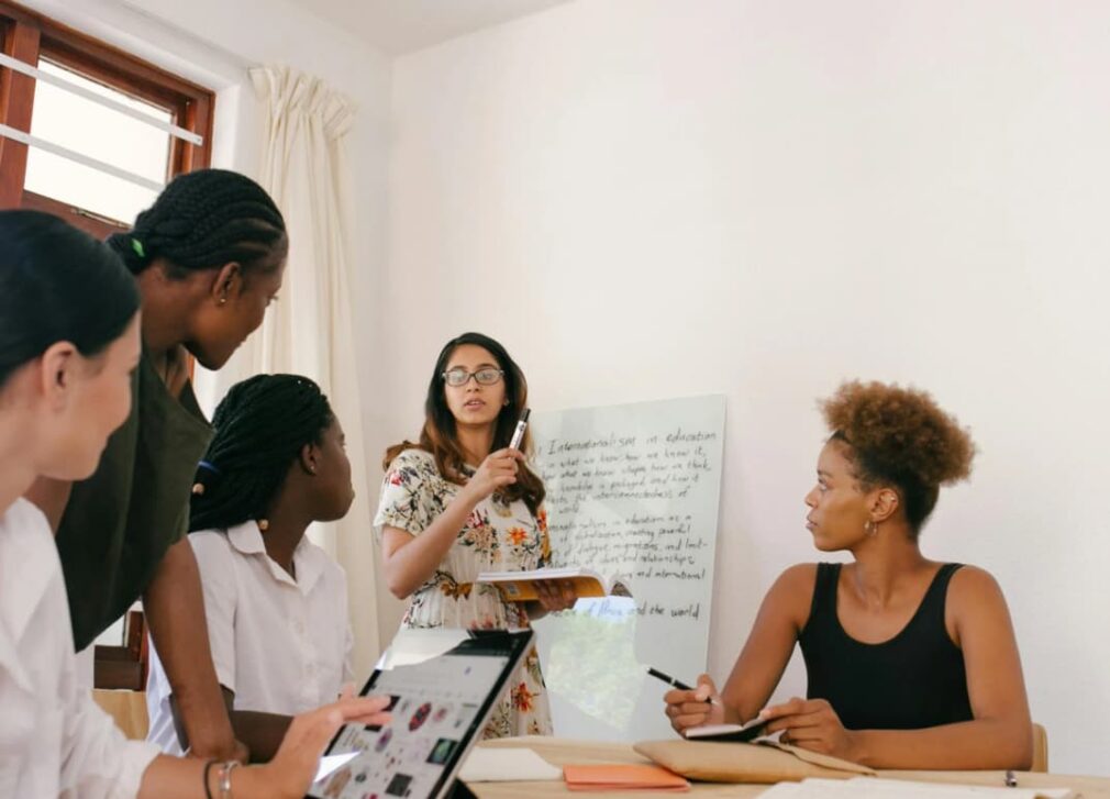 Team meeting with a woman presenting on a whiteboard